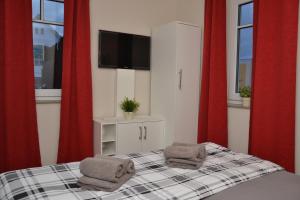 ヘリングスドルフにあるVilla Ilseのベッドルーム1室(赤いカーテン、ベッド1台、タオル2枚付)
