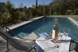 una botella de vino sentada en una mesa junto a la piscina en Meline, en Seillans