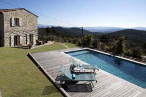 a swimming pool with two chairs and a house at Meline in Seillans