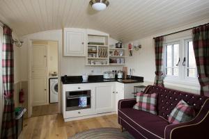 a living room with a couch and a kitchen at The Hideaway Huts in Bardon Mill