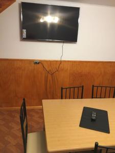 TV en una pared sobre una mesa con sillas en Cabañas Rayen, en Río Bueno