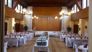 un salón de banquetes con mesas y sillas blancas y lámparas de araña en Hotel Restaurant Hellas, en Gelting