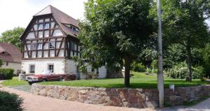 a house with a tree and a stone wall at Ferienwohnung "Alte Bauernstube" in Meißen