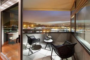einen Balkon mit 2 Stühlen und einem Tisch auf einem Gebäude in der Unterkunft Eurostars Grand Marina Hotel GL in Barcelona
