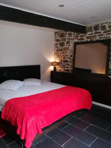 a bedroom with a red blanket on a bed with a brick wall at Le moulin in Pornic