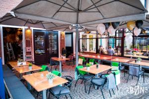 a restaurant with wooden tables and green chairs at Maison Bon Apartments in Den Bosch