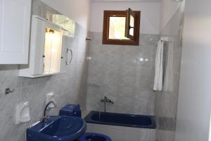 a bathroom with a blue sink and a tub at Katerina Rooms in Syvota