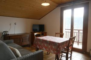 een woonkamer met een tafel, een bank en een televisie bij Abeille Saint Michel in Marthod