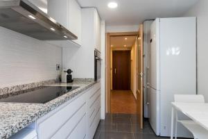 eine Küche mit weißen Arbeitsflächen und einem weißen Kühlschrank in der Unterkunft ApartUP Mestalla Home in Valencia