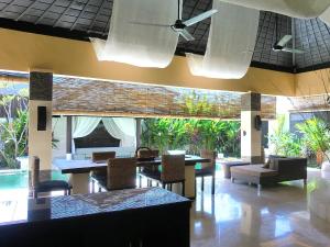 ein Esszimmer mit Tischen, Stühlen und einem Pool in der Unterkunft Nike Villas in Sanur