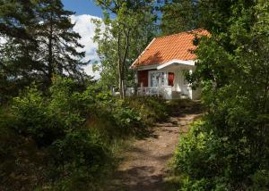 une petite maison blanche avec un toit rouge dans l'établissement Sjöstuga vid Bunn Gränna - Uddastugan, à Gränna