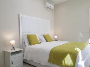 una camera bianca con un grande letto con cuscini gialli di B&B Via Cavour 32 a Siracusa