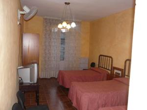 ein Hotelzimmer mit zwei Betten und einem Fernseher in der Unterkunft Hostal Adarnius in La Bisbal