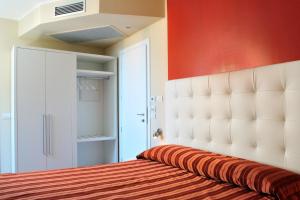 1 dormitorio con cabecero blanco y pared roja en Hotel Villa Molinari, en Collecchio