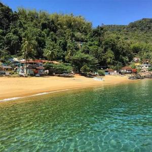 widok na plażę z drzewami i wodą w obiekcie Nena's Suítes w mieście Praia de Araçatiba