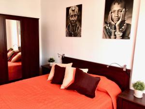プエルト・デ・モガンにあるSabana - Terraza y Vistasのベッドルーム1室(壁に2枚の写真が飾られたオレンジ色のベッド1台付)