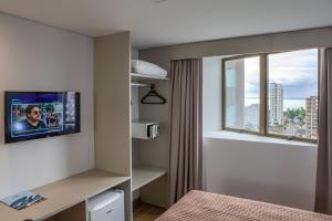 a hotel room with a tv and a window at Marante Executive Hotel in Recife