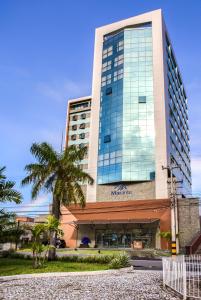a tall building with a palm tree in front of it at Marante Executive Hotel in Recife