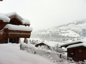 una casa ricoperta di neve con montagne sullo sfondo di AvenidA Panorama Chalet by Alpin Rentals a Piesendorf