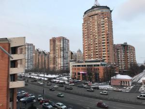 una ciudad con edificios altos y un aparcamiento con coches en Sunny apartment overlooking the royal village, en Kiev