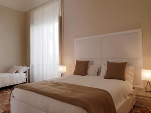 シラクーサにあるB&B Via Cavour 32のベッドルーム(白い大型ベッド、ランプ2つ付)