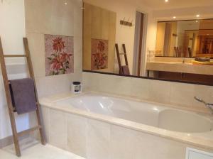 a bathroom with a large tub and a mirror at Villa Le Clos Fleuri in Narbonne