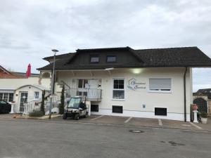 Un bâtiment blanc avec une voiture garée devant. dans l'établissement Gästehaus Elzblick, à Rust