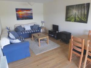 a living room with a blue couch and a table at Trefoil Holiday Home in Strachur