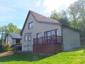 a small house with a large deck on a yard at Trefoil Holiday Home in Strachur