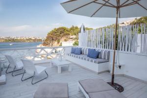 a patio with a couch and chairs and an umbrella at Fonduco in Mahón