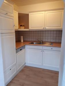 uma cozinha com armários brancos e um lavatório em Ferienwohnung Gashi em Winterberg