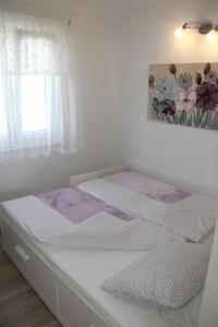 a white bed in a room with a window at Lari Home in Primošten