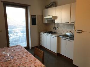 une cuisine avec des placards blancs, une table et une fenêtre dans l'établissement Affittacamere Fiumicello, à Papariano