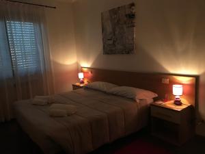 Affittacamere Fiumicello في Papariano: غرفة نوم بسرير كبير ومصباحين على الطاولات