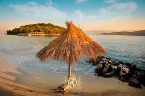 a straw umbrella sitting on a beach next to the water at Private Apartment Jolanda in Sarande in Sarandë