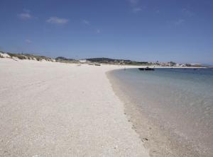 a sandy beach with a boat in the water at Ático en Aguiño by Cristian&Tamara "alquileres" in Ribeira