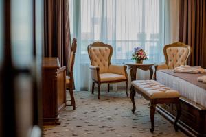 une chambre d'hôtel avec un lit, des chaises et une fenêtre dans l'établissement Almar Luxury, à Mamaia Nord – Năvodari
