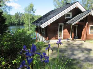 a log cabin with purple flowers in front of it at Vuorenhelmi in Rutalahti