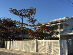 una cerca blanca frente a una casa con un árbol en Residencial Leone, en Bombinhas