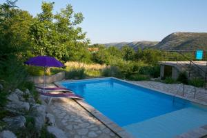 einen Pool mit einem lila Sonnenschirm und einem Stuhl mit in der Unterkunft Abeona Mediterranean Villa in Drivenik