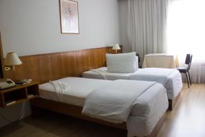 a hotel room with two beds and a desk at Hotel Portal in Santana do Livramento