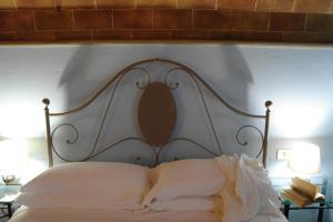 Cama blanca con cabecero de madera y almohadas en Antico Casale Rodilosso, en Montaione