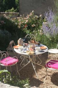 una mesa y sillas en un jardín con comida. en Chambre d'hôtes La Romarine, en Barnave