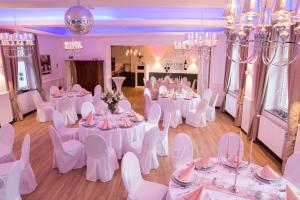 a room with white tables and chairs and chandeliers at Pension zur Sonne 24/7 in Poppenhausen