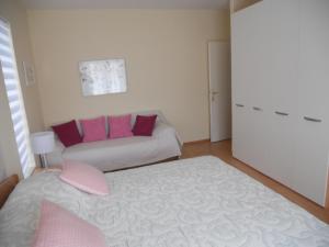 Habitación con cama y sofá con almohadas rosas. en Apartments Mihalić, en Baška