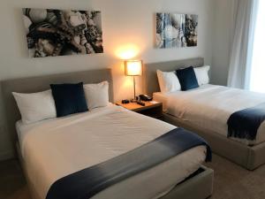 a hotel room with two beds and a lamp at Beach Walk Resort De Lux Apartment in Hallandale Beach