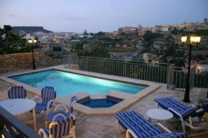 una piscina con sillas y una mesa con vistas en Sylvia' s Millhouse, en Kerċem