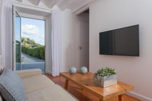 a living room with a couch and a tv on a wall at Quinta de Santa Clara in Ponta Delgada