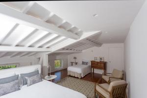 a white bedroom with two beds and a desk at Quinta de Santa Clara in Ponta Delgada
