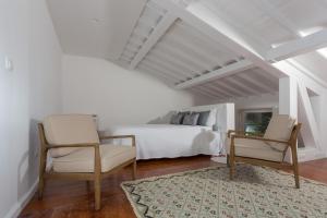 a bedroom with a bed and two chairs and a table at Quinta de Santa Clara in Ponta Delgada